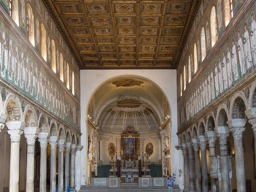 Mittelschiff der Basilica di Sant'Apollinare Nuovo in Ravenna, gesäumt von den byzantinischen Mosaikprozessionen der Jungfrauen und Märtyrer aus dem 6. Jahrhundert über den Säulenarkaden